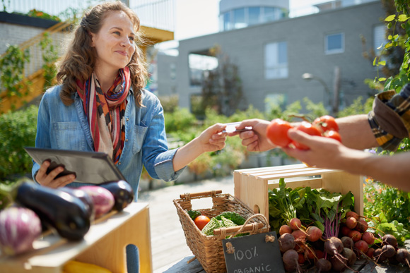 woman purchasing tomatoes at a farmers market