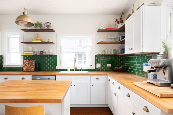 white kitchen with butcher-block counters and green backsplash