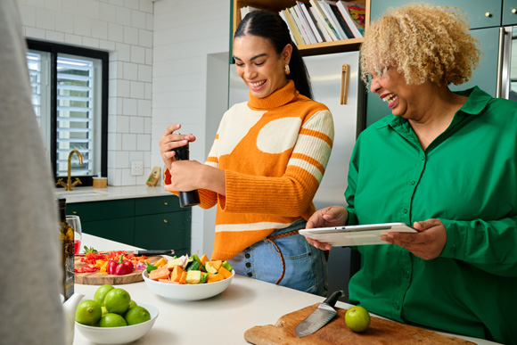 women making salad in a home kitchen