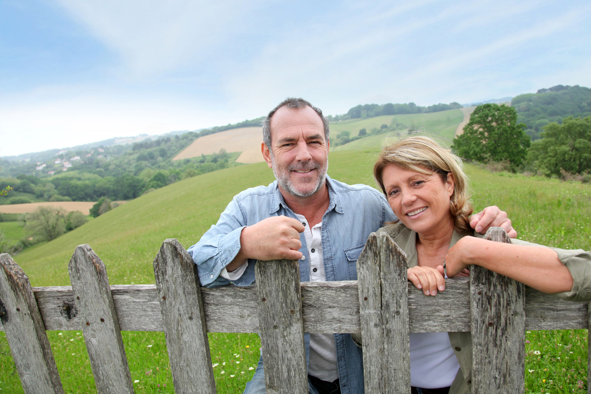 Senior couple leaning on fence in countryside